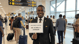 Professional TripEase chauffeur at airport with welcome sign